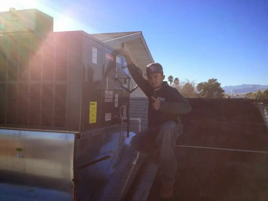 HVAC technician performing Air Duct Cleaning on a rooftop unit in Waller